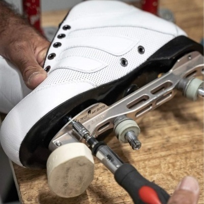 Patins de rodas brancos a ser apertados com ferramenta numa bancada de madeira