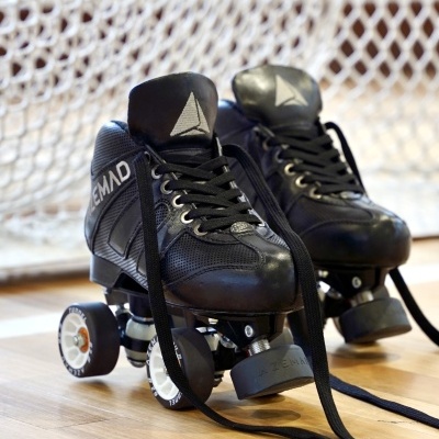 Patins em linha pretos com rodas, sobre piso de madeira