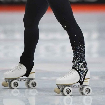 Patins brancos de rodas usados com leggings pretas decoradas em pista de patinagem