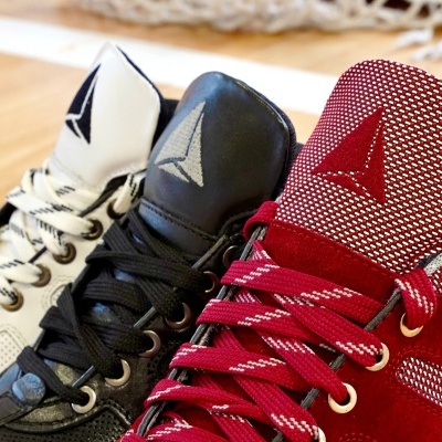 Três sapatilhas desportivas branca, preta e vermelha com atacadores e logotipo triangular