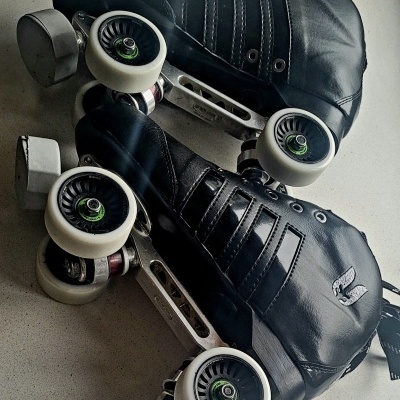 Patins de rodas pretos com rodas brancas sobre superfície cinza