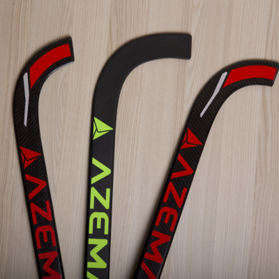 Três tacos de hóquei azuis e vermelhos sobre madeira clara