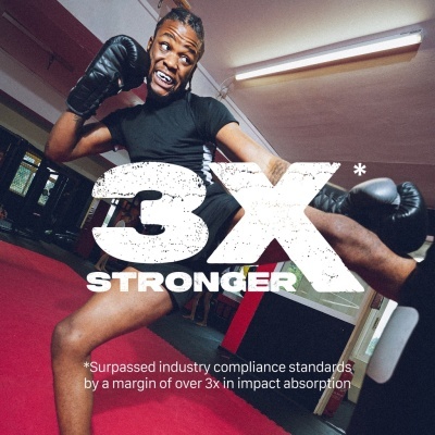 Homem a praticar boxe numa sala com tatami vermelho usando luvas de boxe pretas.