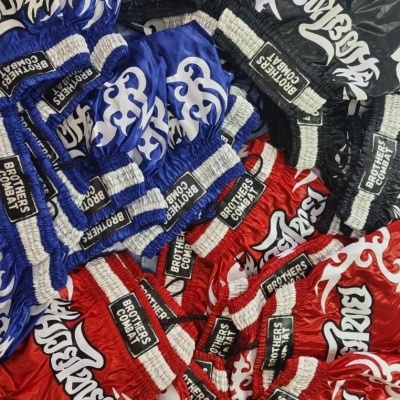 Luvas de combate Muay Thai em nylon azul, vermelho e preto com estampas brancas e etiquetas BROTHERS COMBAT