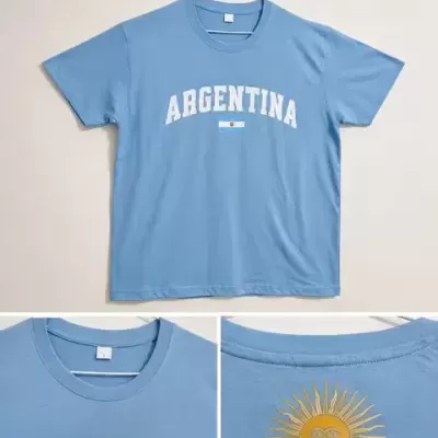 T-shirt azul clara com texto ARGENTINA e bandeira na frente, sol amarelo nas costas