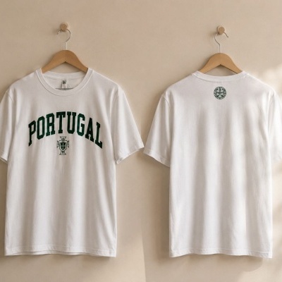 Duas t-shirts brancas com texto Portugal e símbolos verdes penduradas em cabides de madeira