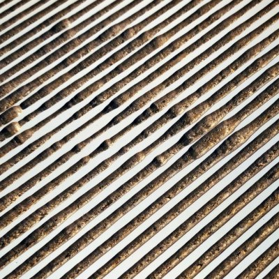 Estrutura metálica com ripas brancas e terra visível entre elas