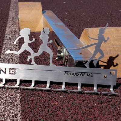 Suporte metálico para medalhas com figuras femininas a correr e texto 'PROUD OF ME'