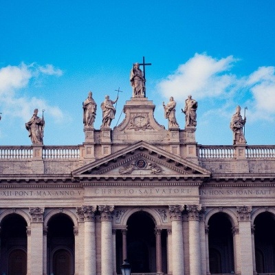 Fachada clássica com colunas e estátuas sob céu azul