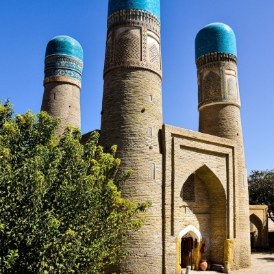 Torres cilíndricas com cúpulas azuis e entrada arqueada em monumento de tijolos