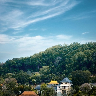 Casas tradicionais junto a lago com colina verde e céu azul