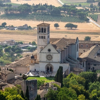 Igreja antiga de pedra com torre e campos ao redor vista de cima