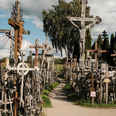 Caminho ladeado por cruzes de madeira e metal com representações de Cristo ao ar livre