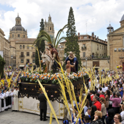 Procissão religiosa com estátuas e multidão em praça histórica