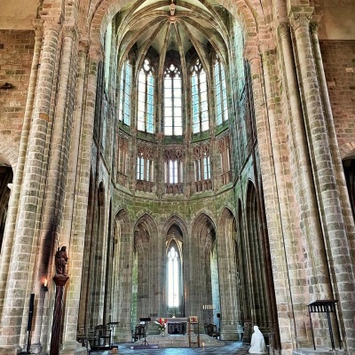 Interior de uma catedral gótica com colunas de pedra e bancos de madeira