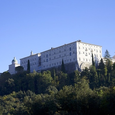 Edifício grande em pedra clara no topo de uma colina com árvores verdes
