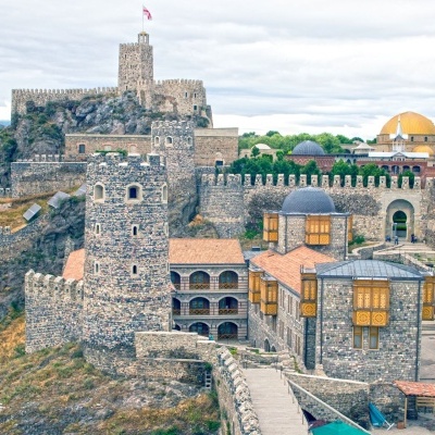 Fortaleza histórica de pedra cinzenta com torres e muralhas em encosta rochosa