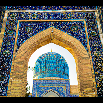 Cúpula azul decorativa vista através de um arco de tijolos amarelos com azulejos azuis