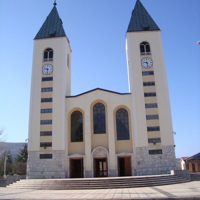 Igreja com duas torres e relógios, estrutura branca e céu azul