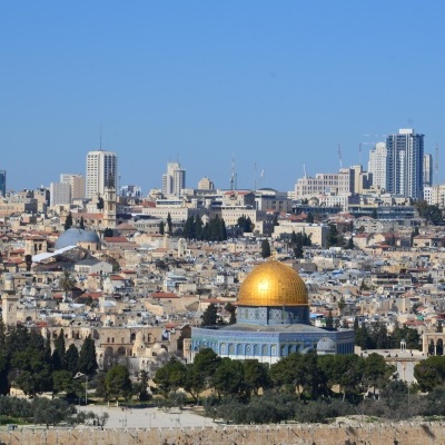 Cidade com cúpula dourada e edifícios ao fundo sob céu azul