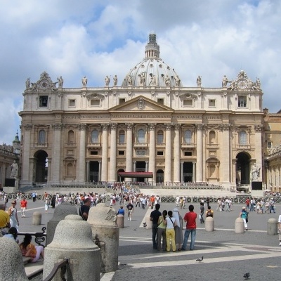 Edifício clássico com cúpula e colunas visto de uma praça com pessoas