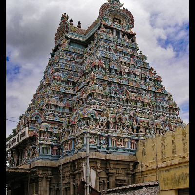 Templo hindu com torre colorida e esculturas detalhadas sobre céu nublado