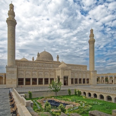 Mesquita grande com dois minaretes e jardim interno sob céu nublado