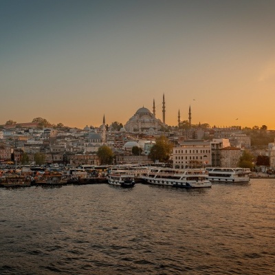 Cidade costeira ao pôr do sol com barcos e mesquita ao fundo