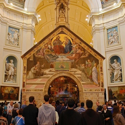 Interior de igreja com frescos religiosos e pessoas, incluindo quatro com vestes religiosas.