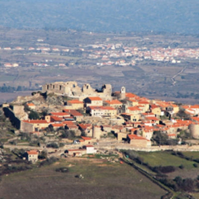 Vista aérea de vila histórica em colina com telhados vermelhos e paisagem rural