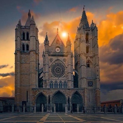 Catedral gótica em pedra com torres e rosácea ao pôr do sol