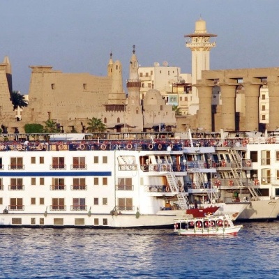 Navios de cruzeiro brancos ancorados no rio em frente a antiga construção de pedra