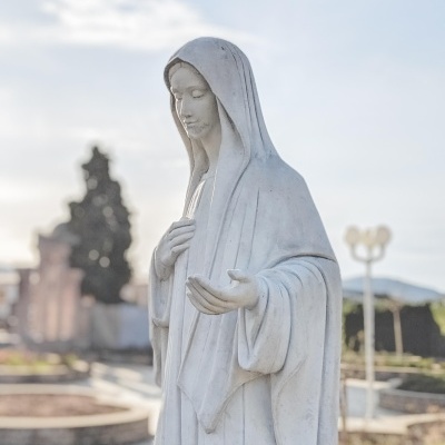 Estátua branca de figura feminina com capuz ao ar livre