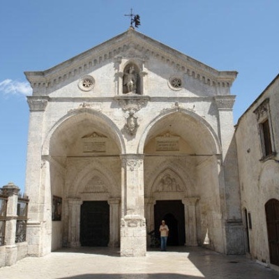 Entrada de edifício histórico com três arcos e portas escuras sob céu azul