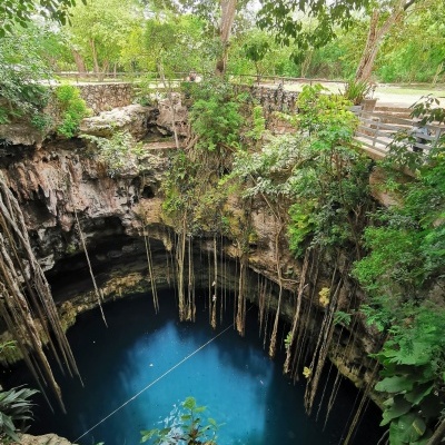 Cenote natural com água azul turquesa, rochas e vegetação
