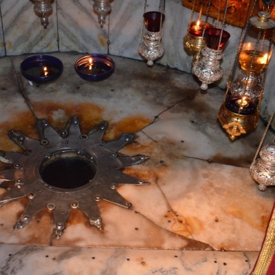 Base circular em mármore com padrão metálico em forma de estrela e objetos metálicos pendurados.