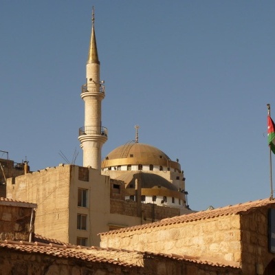 Edifícios com mesquita e bandeira jordaniana ao fundo