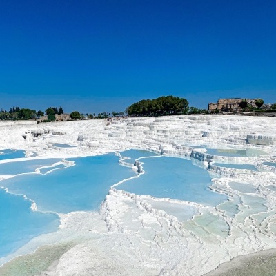 Piscinas naturais em cascata com água azul clara e terreno branco calcário