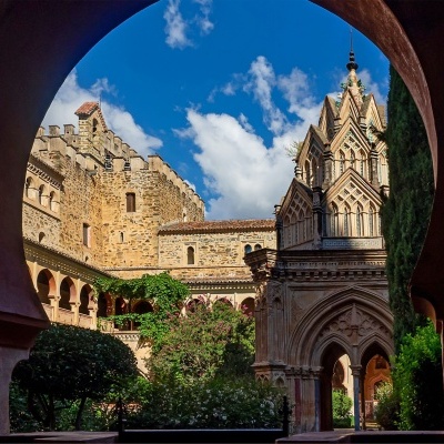 Arquitetura histórica com arcos, torres e vegetação sob céu azul