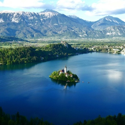 Lago com ilha e igreja rodeado por montanhas e floresta