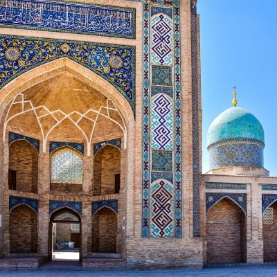 Entrada histórica com arcos em tijolo, azulejos azuis com padrões geométricos e cúpula azul