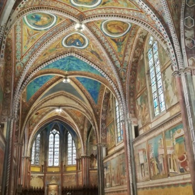 Interior de igreja gótica com frescos coloridos e vitrais altos