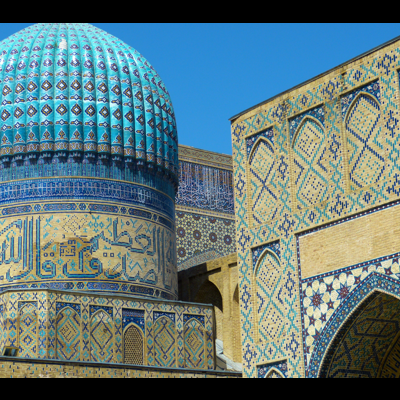 Cúpula azul decorada com azulejos e paredes adjacentes com azulejos geométricos e caligrafia árabe