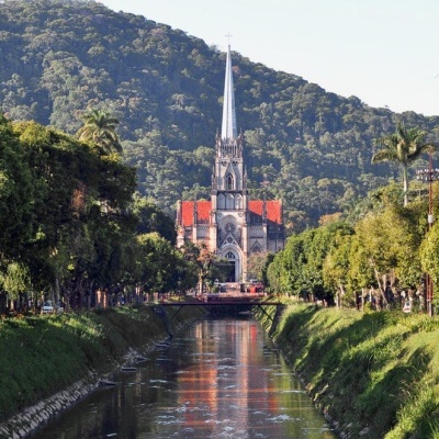 Igreja gótica com torre e canal ladeado de árvores