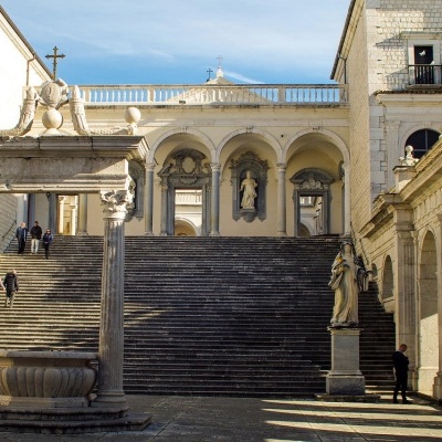 Escadaria de pedra com estátuas em edifício clássico num dia ensolarado
