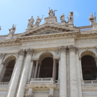 Edifício histórico em pedra com colunas coríntias, estátuas e inscrição em latim