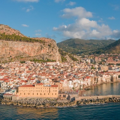 Cidade costeira com edifícios vermelhos, montanhas e mar