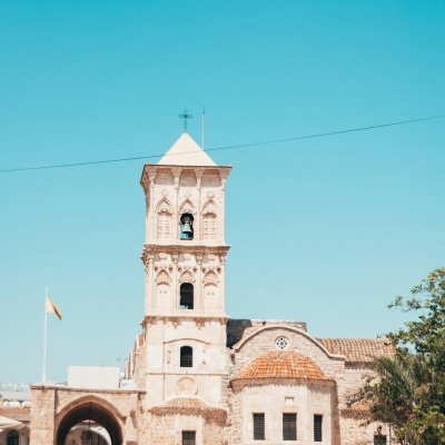 Edifício histórico de pedra com torre sineira e telhado de telha vermelha em dia ensolarado