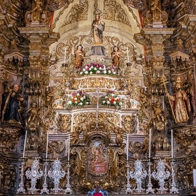 Altar ricamente entalhado em madeira dourada com figuras religiosas e castiçais
