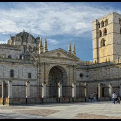 Edifício histórico de pedra cinzenta com torre e cúpula num largo